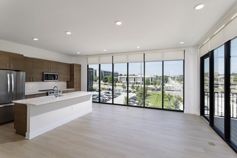 A modern kitchen with a large island and a view of the parking lot outside.