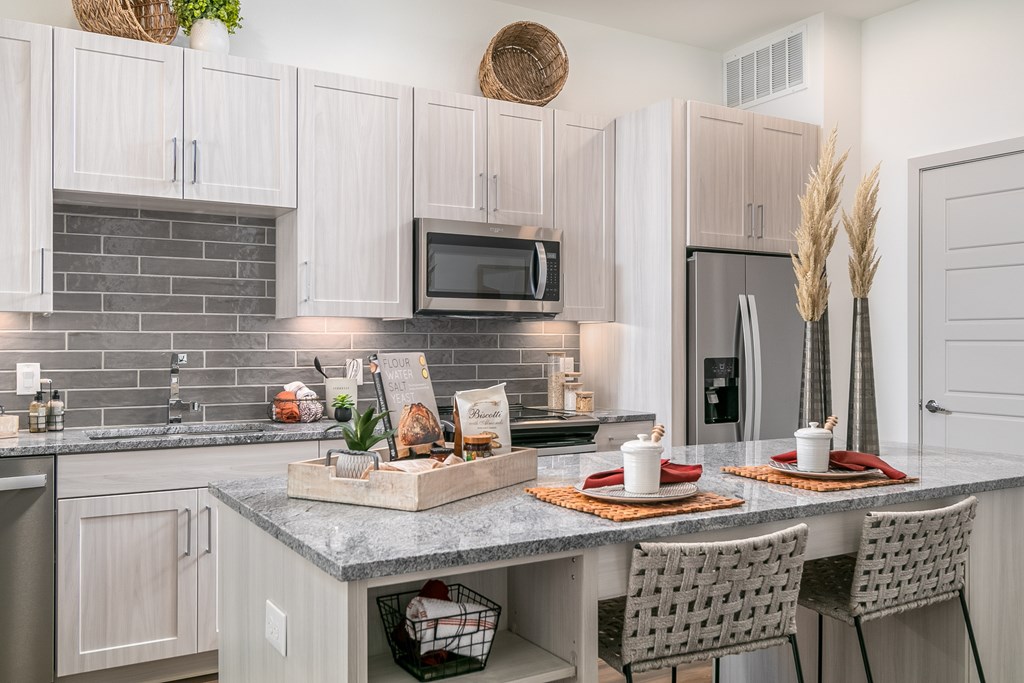 A kitchen with a table set for two with plates and glasses.