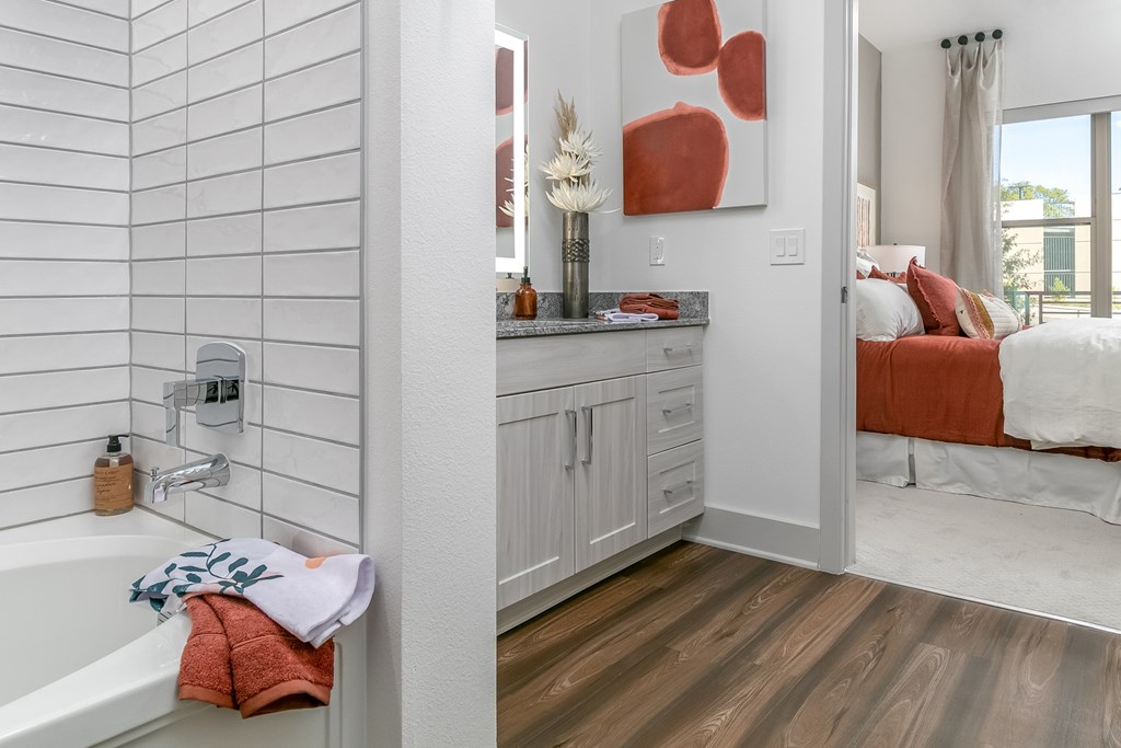 A bathroom with a white tub and a wooden floor.