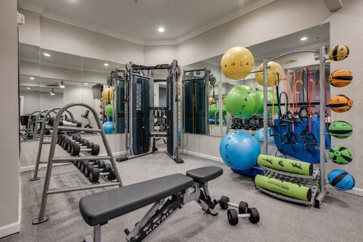 a gym with cardio equipment and weights on the floor