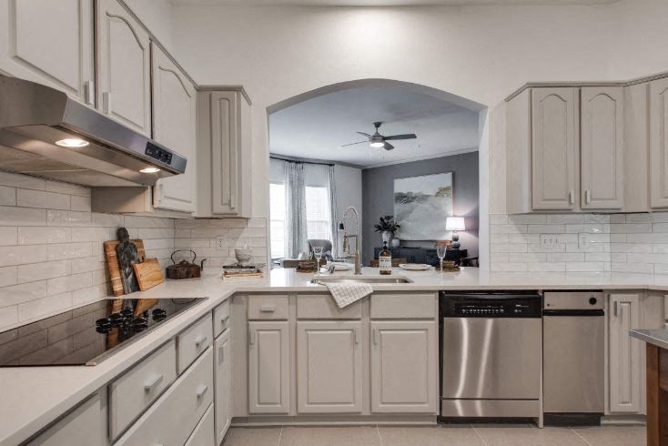 a white kitchen with white cabinets and a silver dishwasher