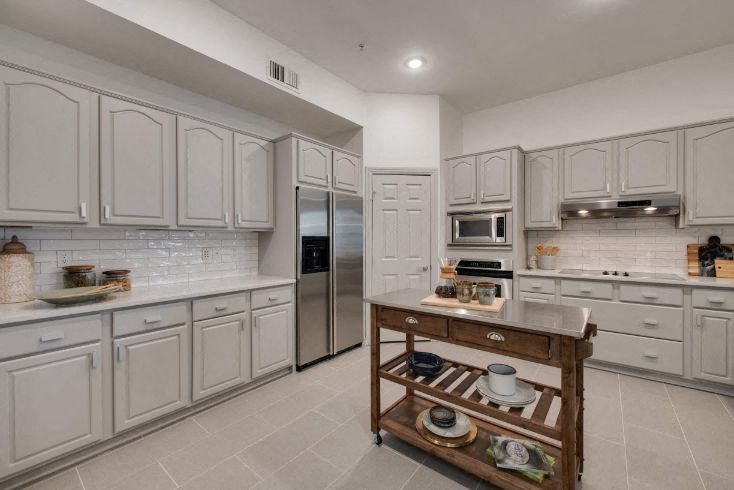 a large kitchen with white cabinets and stainless steel appliances