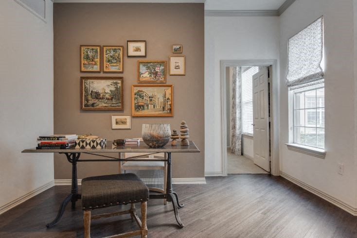 a room with a table and a chair and pictures on the wall