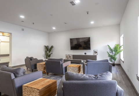 a living room with couches and chairs and a television on the wall