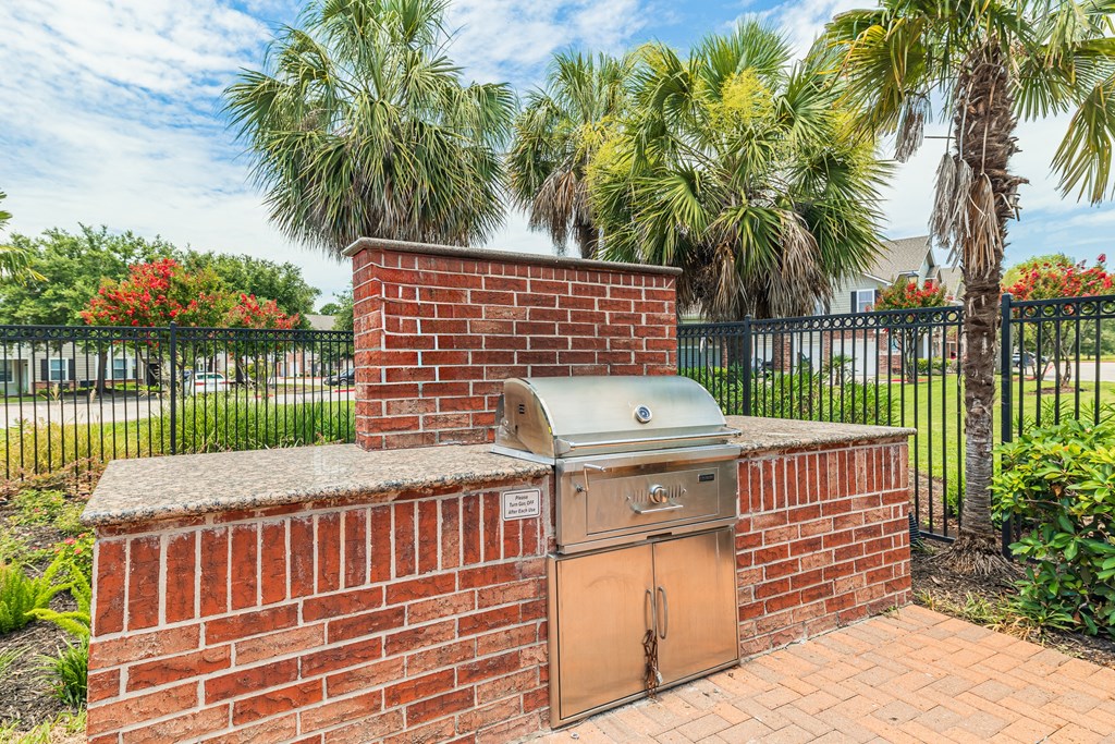 a brick outdoor kitchen with a grill and palm trees