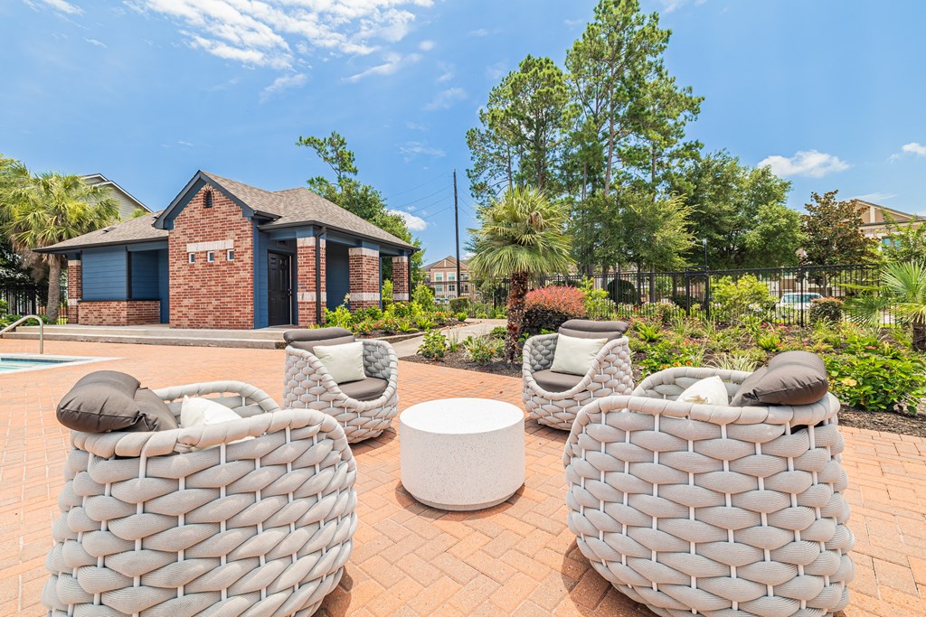 a patio with chairs and a table and a house in the background
