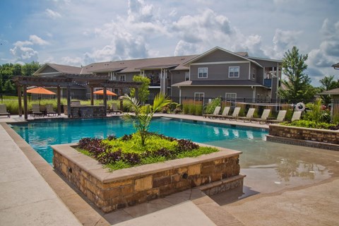 A large swimming pool surrounded by a stone planter with plants in it.