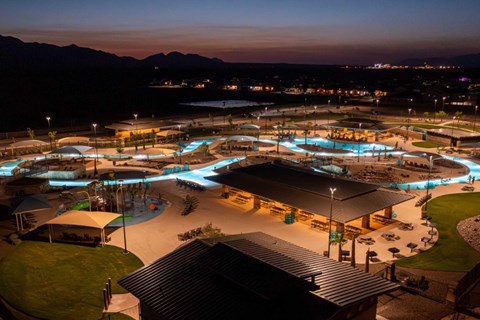 A beautifully lit resort at night with a pool and mountain in the background.