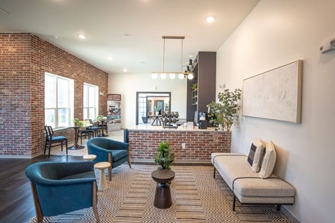 a living room with a couch and chairs and a brick wall