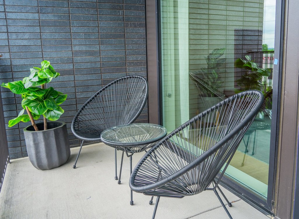 a patio with three chairs and a potted plant
