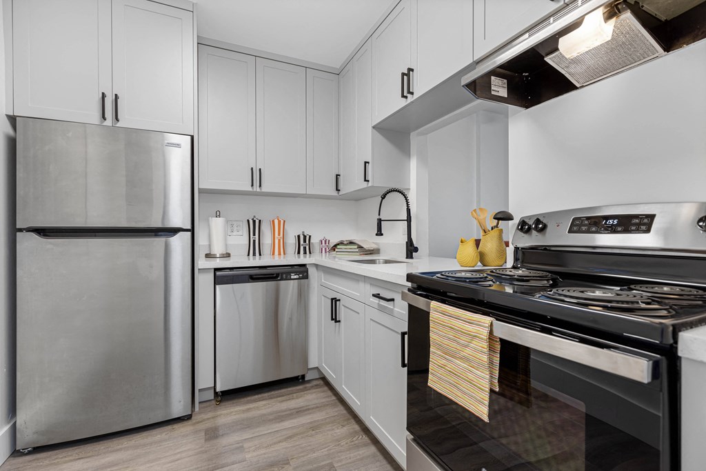 A modern kitchen with a stainless steel refrigerator and a stove with a pot on it.