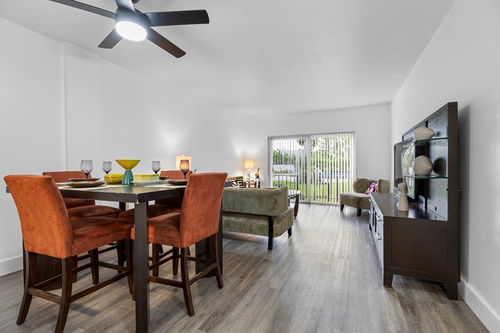 A dining room with a table set for two and a ceiling fan.