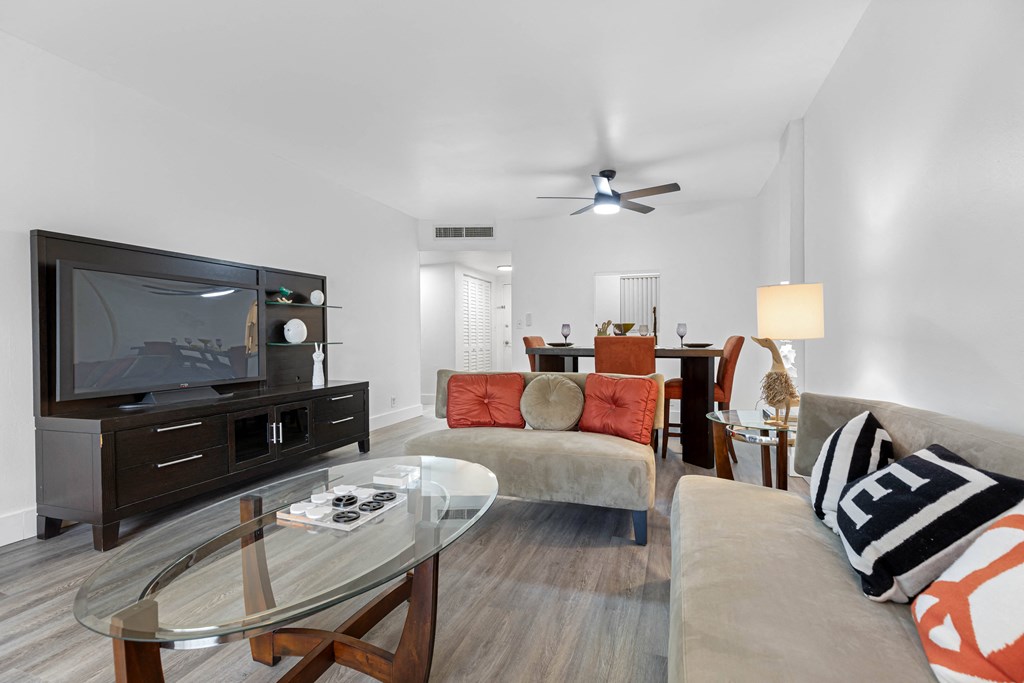 A modern living room with a glass coffee table and a television.