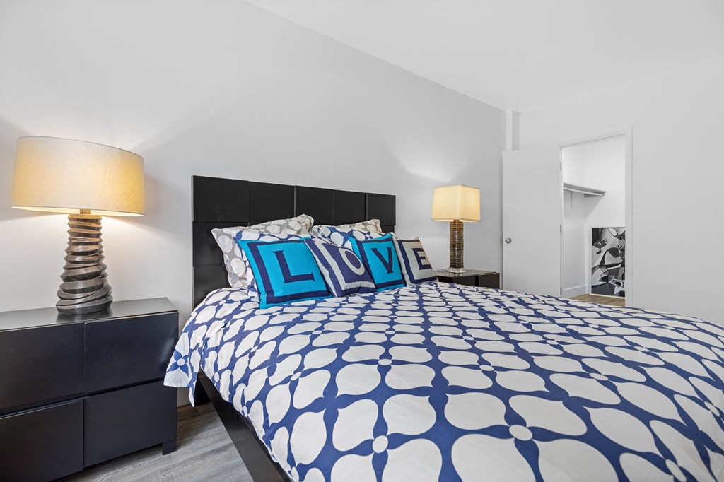 A bed with a blue and white patterned comforter and two matching pillows with the word LOVE written on them.