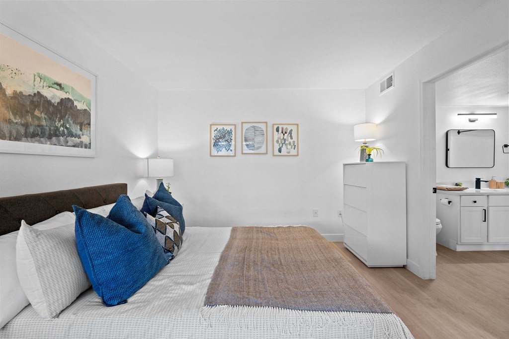 a bedroom with a bed with blue pillows and a rug