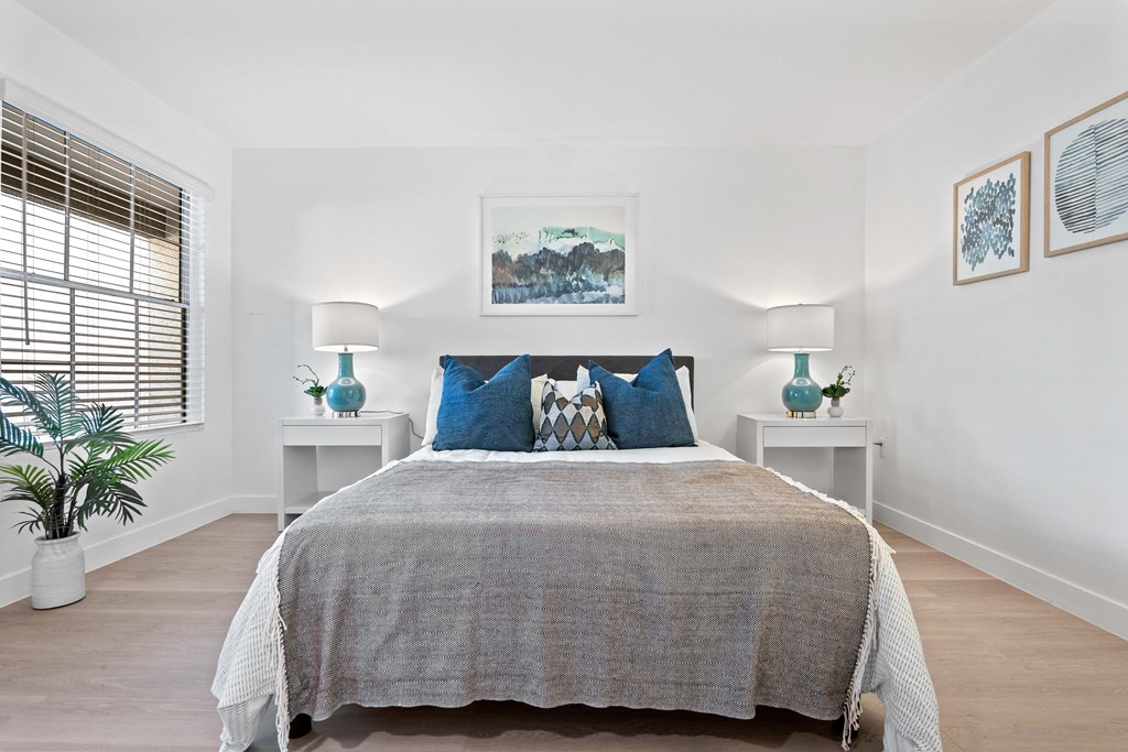 a bedroom with white walls and a bed with blue pillows