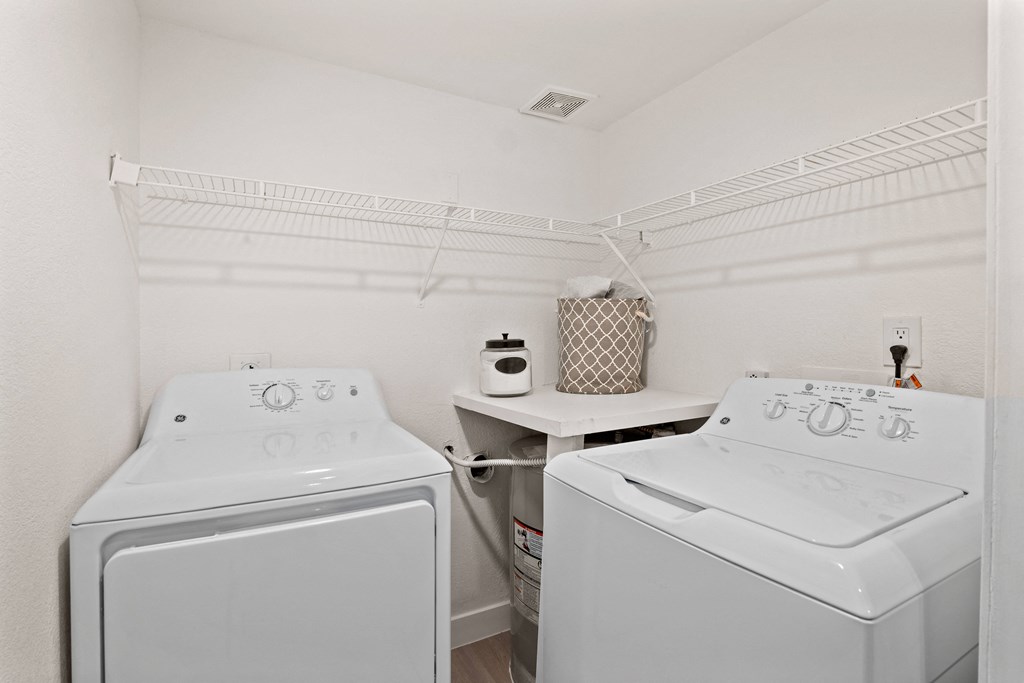 two white washers and dryers in a white laundry room