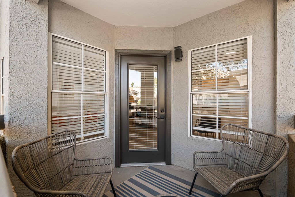 a porch with two chairs and a door