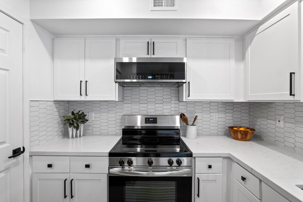 a white kitchen with a stove and white cabinets