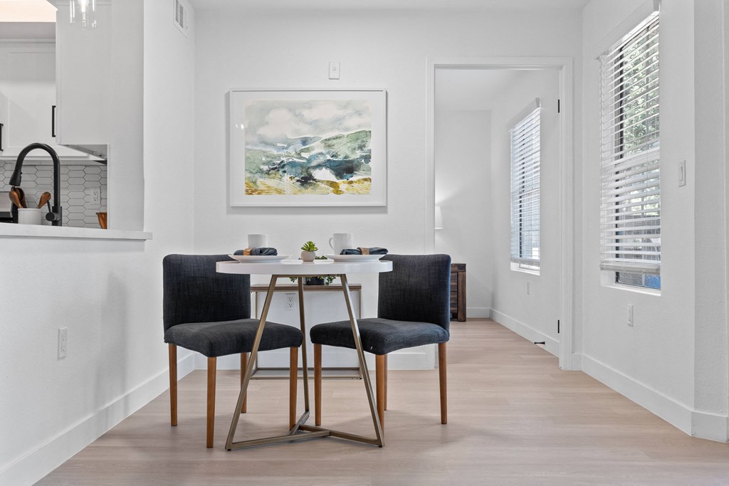 a dining room with a white table and two black chairs