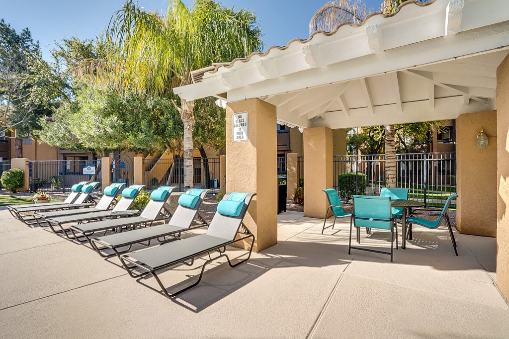a patio with chaise lounge chairs and a pergola