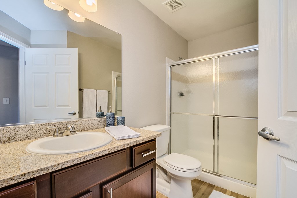 a bathroom with a toilet sink mirror and shower