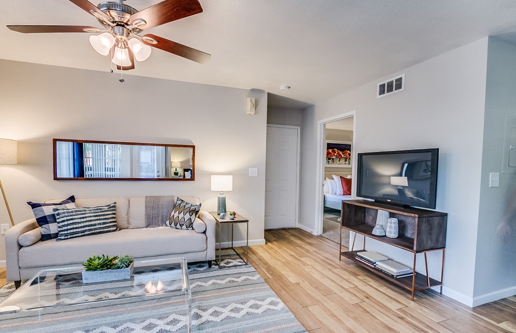 a living room with a ceiling fan and a flat screen tv
