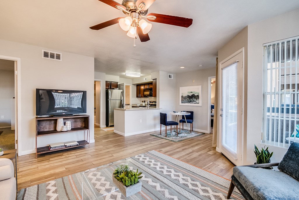 a living room with a ceiling fan and a door leading to a kitchen