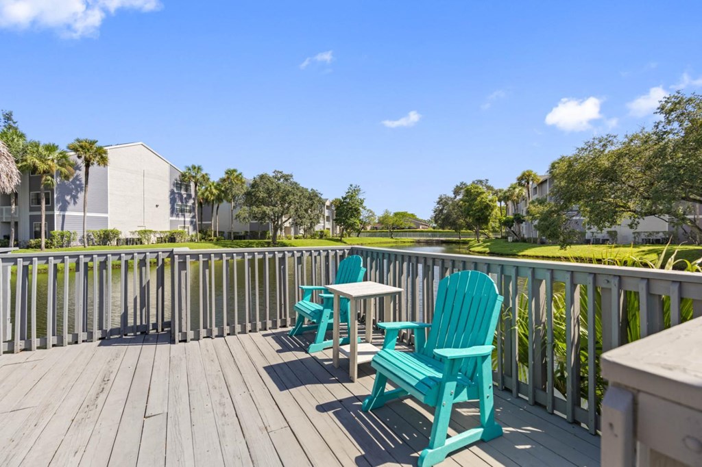 a deck with two blue chairs and a table on it