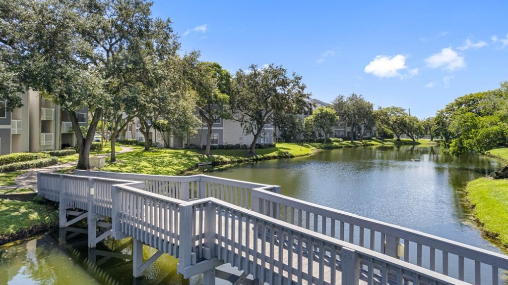 A white bridge over a body of water with trees in the background.