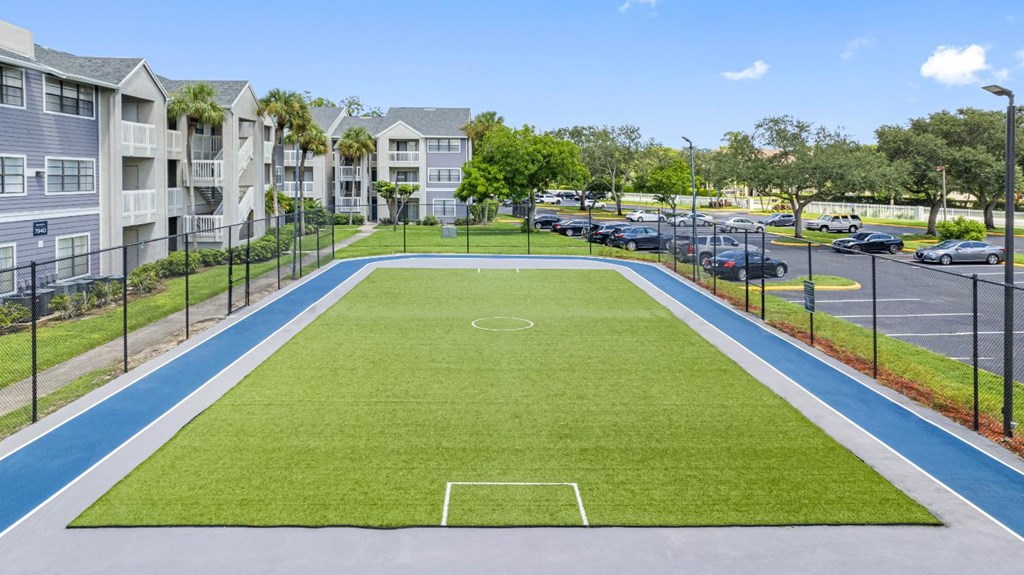 a soccer field in the middle of a parking lot with apartments in the background