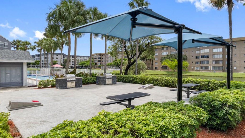 a picnic area with picnic tables and umbrellas next to a pool