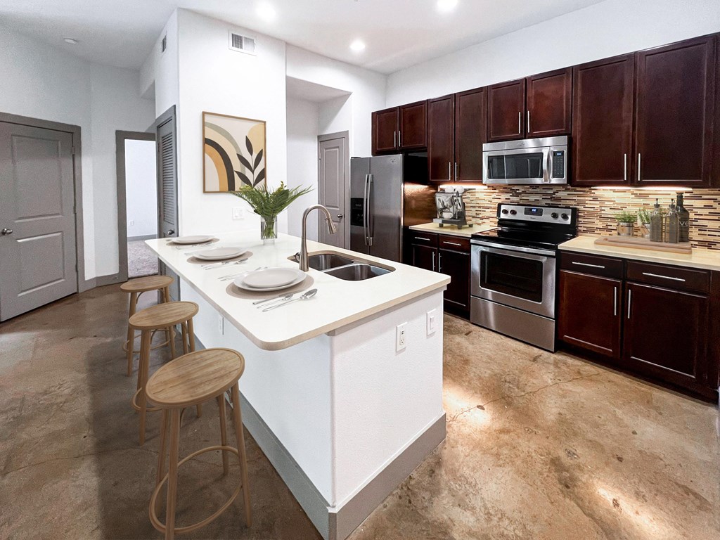 a kitchen with a large center island with a sink and two stools