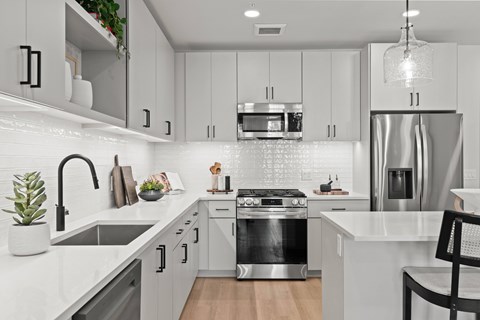 A modern kitchen with a stainless steel refrigerator and a black chair.