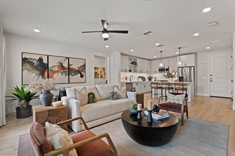 A modern living room with a large painting on the wall and a coffee table in the center.