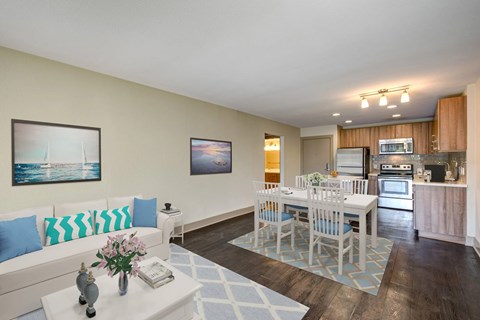 A living room with a white couch and a dining table with chairs.