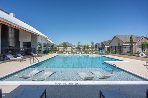 a swimming pool with lounge chairs in front of a house