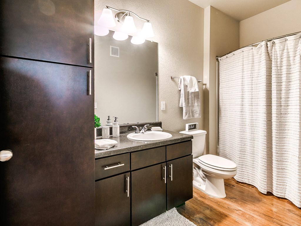 a bathroom with dark cabinets and a white shower curtain