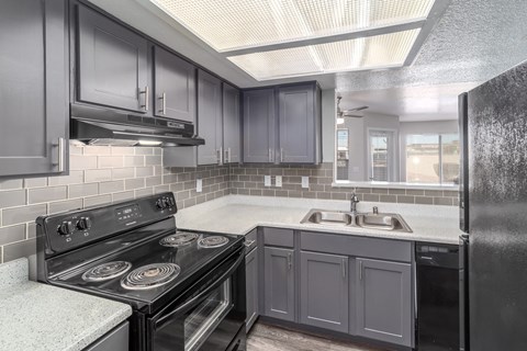 a kitchen with black appliances and gray cabinets
