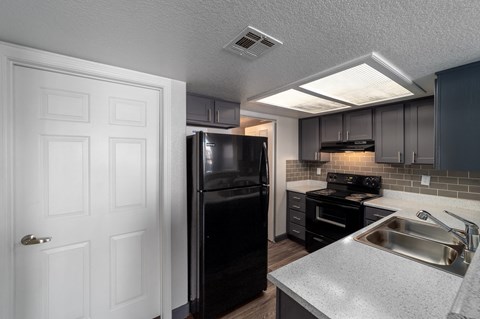 a kitchen with a sink and a black refrigerator