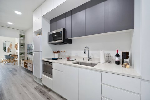 A modern kitchen with white cabinets and a grey backsplash.