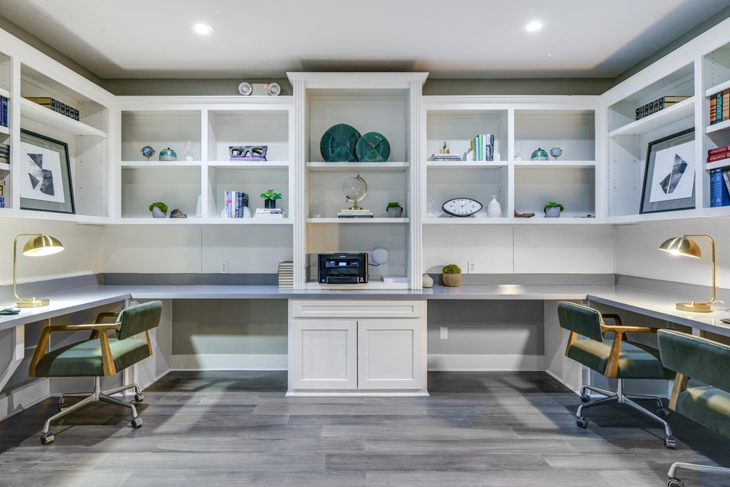 a home office with two desks and chairs and white shelves