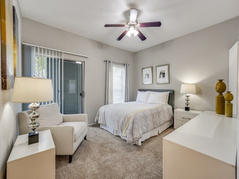 A bedroom with a bed, nightstand, and chair.