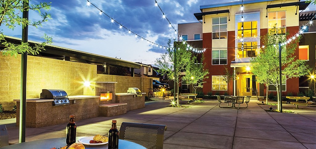a patio with a grill and tables at night