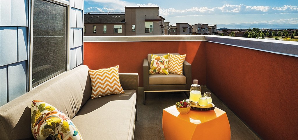 a balcony with couches and a table with a bottle of wine