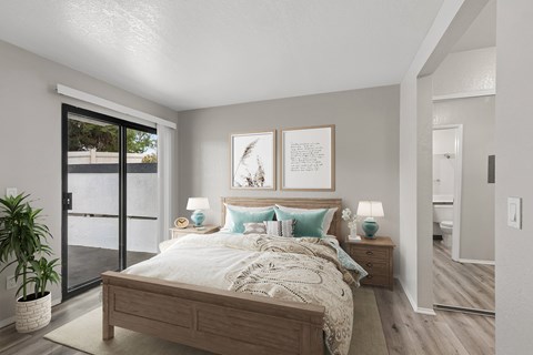 A bedroom with a large bed and a potted plant.