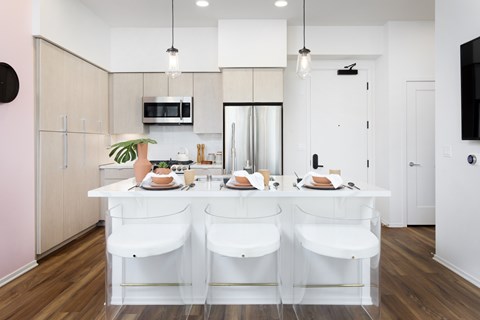 A kitchen with white chairs and a white table with food on it.
