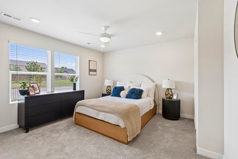 A bedroom with a large bed and a window with a view of a fence and trees.