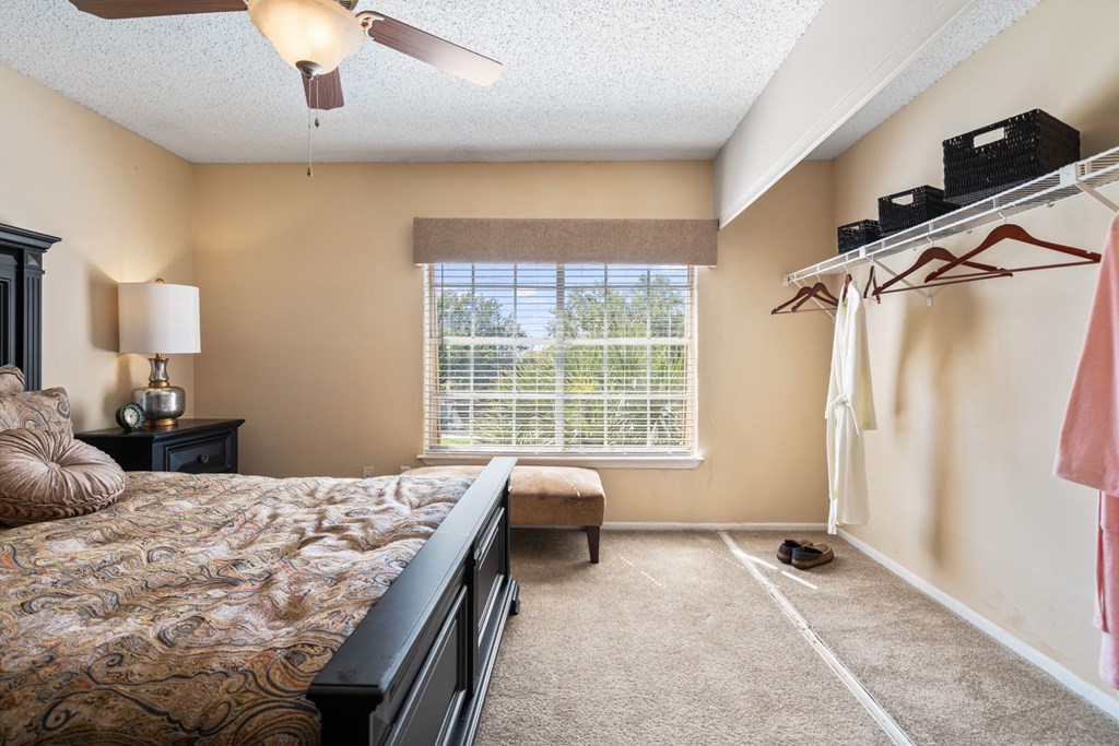 a bedroom with a large window and a ceiling fan