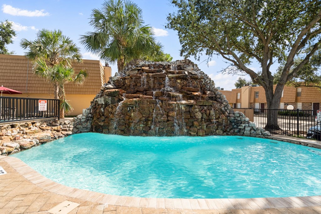 a large pool with a rock waterfall in the middle of it